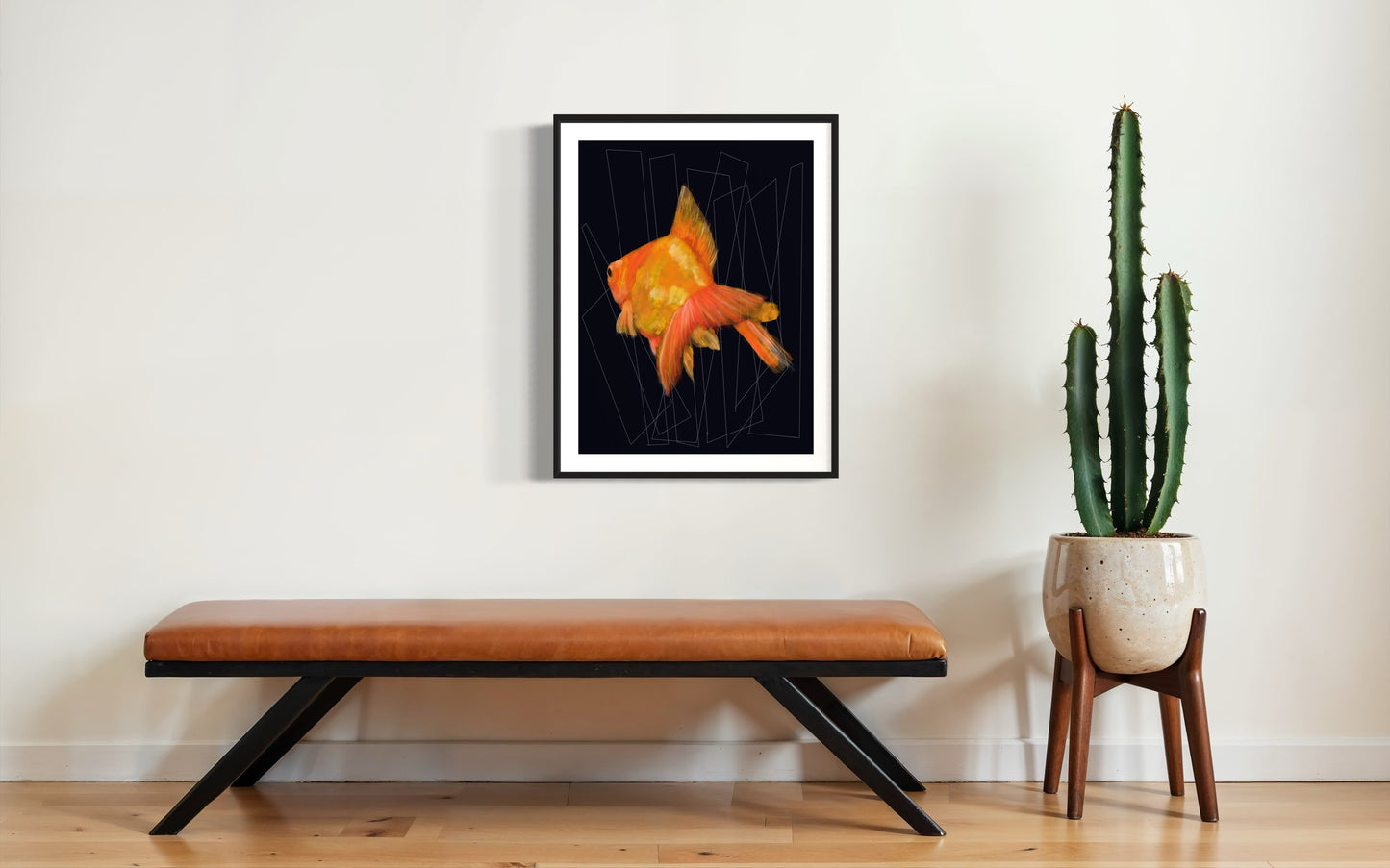 Cuadro de pez dorado con fondo negro y geometría sutil en pared blanca junto a cactus.